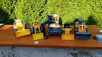 Four yellow construction vehicle toys on tabletop