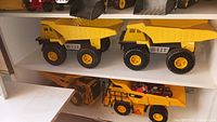 Shelves showing CAT dump truck, CAT loader, two identical large dump trucks, two compact loaders