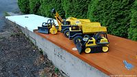 All five Tonka construction vehicles lined up on wooden surface