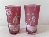Both cranberry glass tumblers standing upright