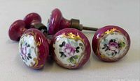 Group view of six porcelain drawer pulls showing floral design and color