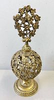 Full view of perfume bottle showing pierced brass leaf design and stopper