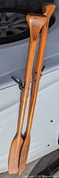 Full view of both wooden oars leaning against vehicle
