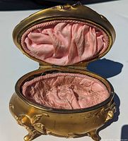 Open view showing pink silk interior and oval hinged lid