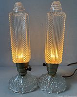 Both lamps lit, showing ribbed column shades and hobnail bases