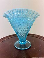 Front view of aqua blue hobnail fan vase on dark surface