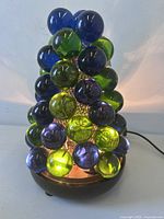 Front view of illuminated lucite grape lamp showing blue, green, purple spheres and wood base