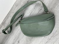 Front view of green leather shoulder purse showing shape, zipper and strap