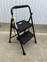 Full view of black two-step folding stool ladder