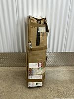 Full view of taped and damaged cardboard box containing tree