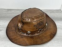 Top view of brown leather cowboy hat with tooled wolf and snake, hatband with conchos