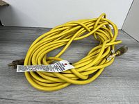 Coiled yellow extension cord showing both ends and safety tag