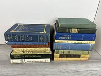 Two vertical stacks of approximately seventeen assorted hardcover books with visible spines