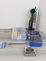 Group shot of all items: bit set, extension bar, measuring tape, cable ties canister, hardware organizer