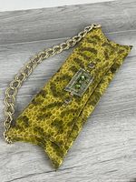 Front view of clutch showing pattern, clasp and chain strap