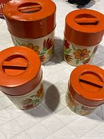 all four nesting canisters showing lids and floral design