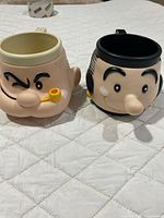 Both plastic cartoon face mugs side by side