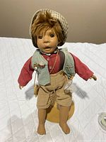 Front view of boy doll on stand with outfit and accessories visible
