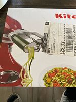 Retail box showing KitchenAid stand mixer with spiralizer attachment and finished vegetable noodles