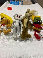 Four Looney Tunes plush figures laid out on bed