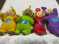 Front view of all four Teletubbies plush dolls on quilt