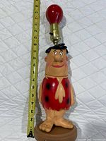 Full view of Fred Flintstone lamp with measuring tape showing 16 in height
