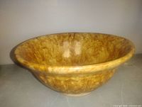 Side view of mottled yellow-brown stoneware bowl showing flared rim and glaze