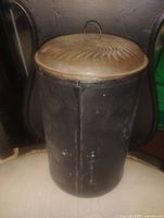 Full view of tin canister with lid on chair
