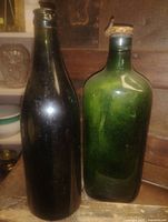 Front view of both antique green bottles standing side by side