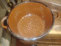Top view showing perforated interior of brown enamel strainer pot