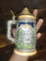 Front view showing alpine cabin scene and pewter lid