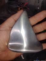 Front view of polished aluminum sailboat sculpture in hand