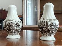 Front view of both shakers showing transferware coach scene