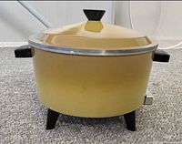 Front view of yellow enamel electric deep fryer on black legs with lid