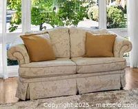 Front view of cream floral loveseat with two tan pillows