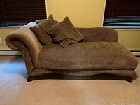 Full view of brown upholstered chaise lounge with pillows