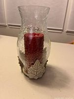 Front view of candle holder showing crackle glass, metal leaf base and red candle inside