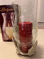 Complete candle holder assembled with red candle inside crackle glass shade, retail box in background