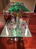 Front view of glass palm tree figurine with two swans on mirrored base