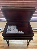 Table shown open to display interior storage compartment