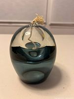 Front view of round light blue glass oil lamp showing wick and coloration