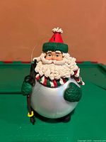 Front view of Santa ornament showing face, hat, mittens, pole, body