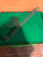 Both scrollwork metal wreath holders on green bin