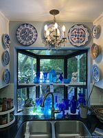 Bay window with blue glass vessels on shelves and decorative plates surrounding