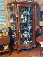 Full view of wood china cabinet with curved glass panels and interior shelves