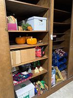 Full view of cabinet shelves showing pumpkins, storage crate, cards, ceramic trees, angels, stockings, boxes