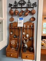 Overall view showing wrought iron rack with copper pieces and two wooden spoon racks with contents