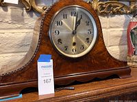 Front view of wood mantel clock on shelf