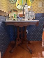 Full view of marble-top table with lamp, plates, glassware