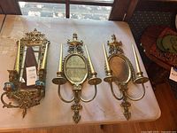 All three gilt mirrored sconces on table with candles visible